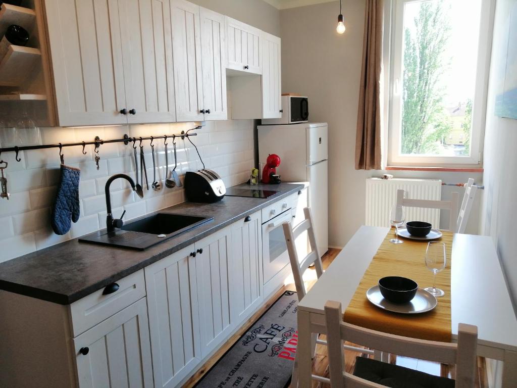 a kitchen with white cabinets and a table and a sink at Panoráma apartman in Tapolca