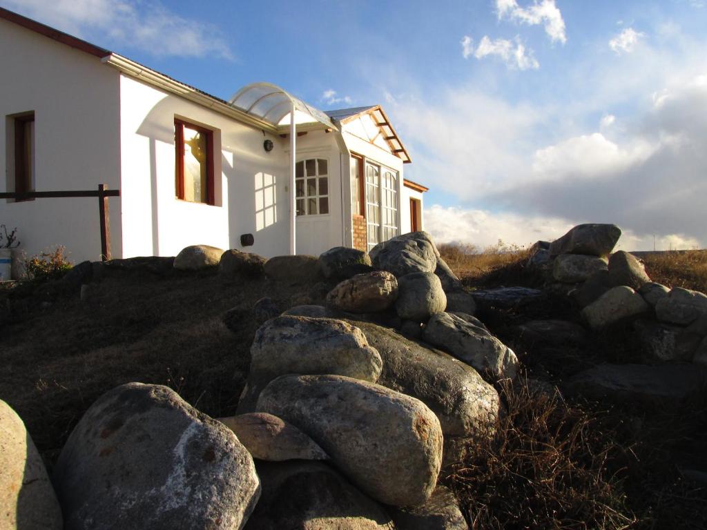 a teddy bear sitting on top of rocks in front of a house at Hostel Aves del Lago in El Calafate