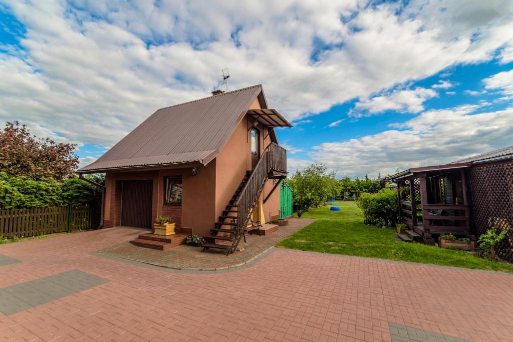 ein kleines Haus mit einem Metalldach auf einer Ziegelsteinfahrt in der Unterkunft Pensjonat Jagoda in Pisz