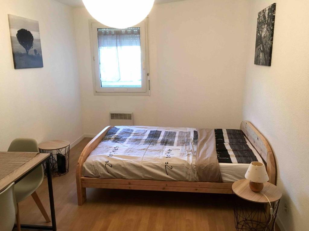 a bedroom with a bed and a table and a window at Studio ARBOLES in Chambéry