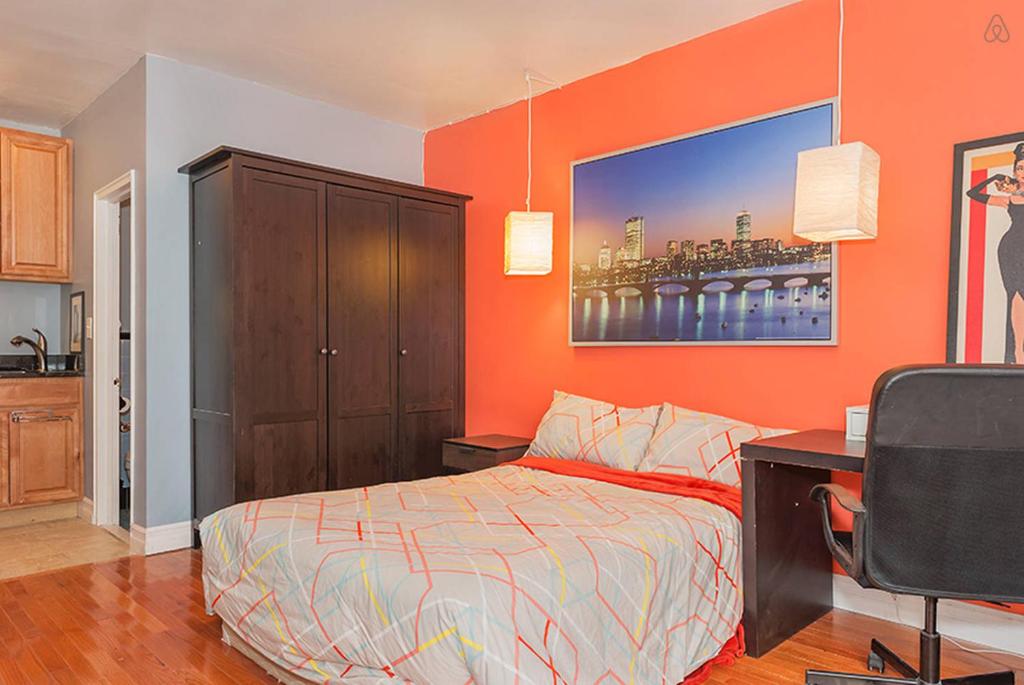 a bedroom with an orange wall with a bed and a desk at Downtown Studio Apt, Short Walk To Hospitals in Boston