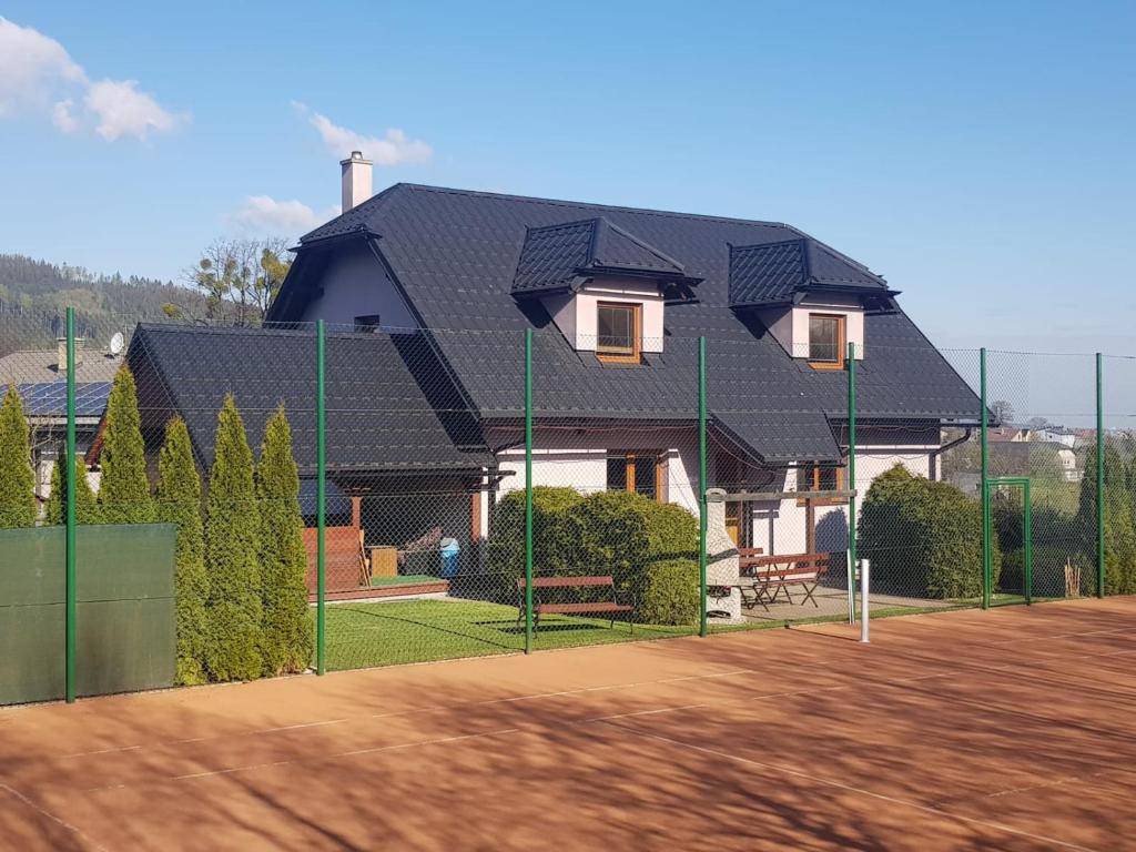 a house with a black roof on a tennis court at Apartmány u tenisového kurtu in Mosty u Jablunkova