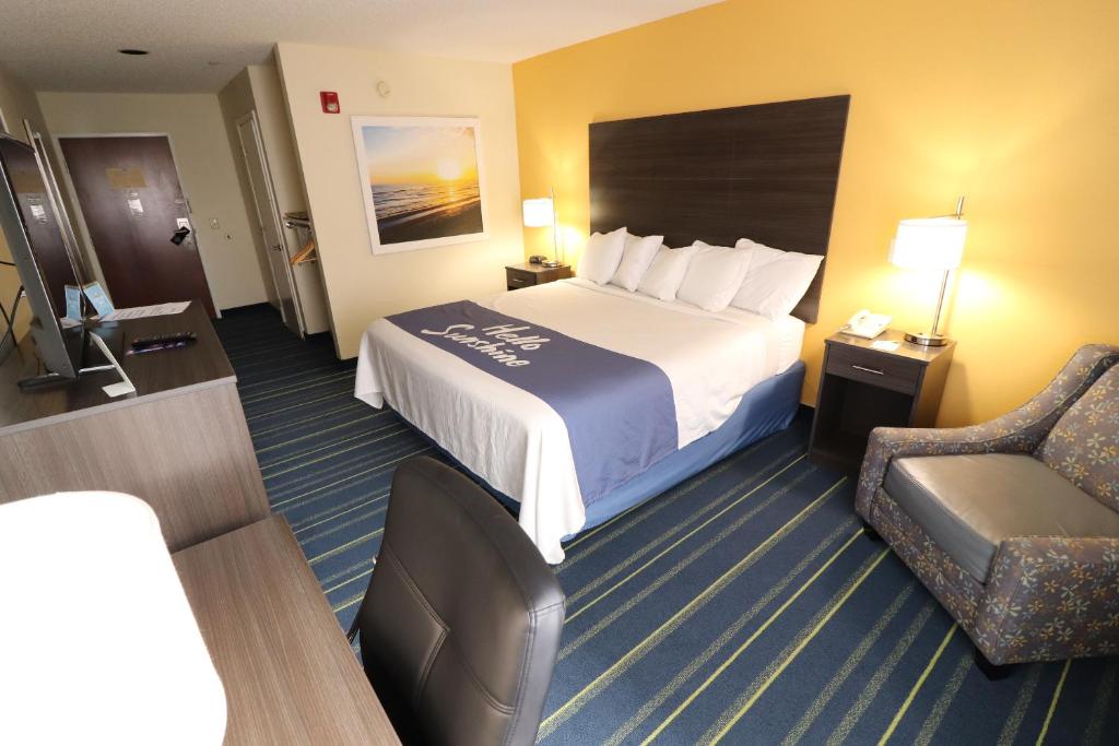 a hotel room with a bed and a chair at Days Inn by Wyndham Burlington East in Haw River