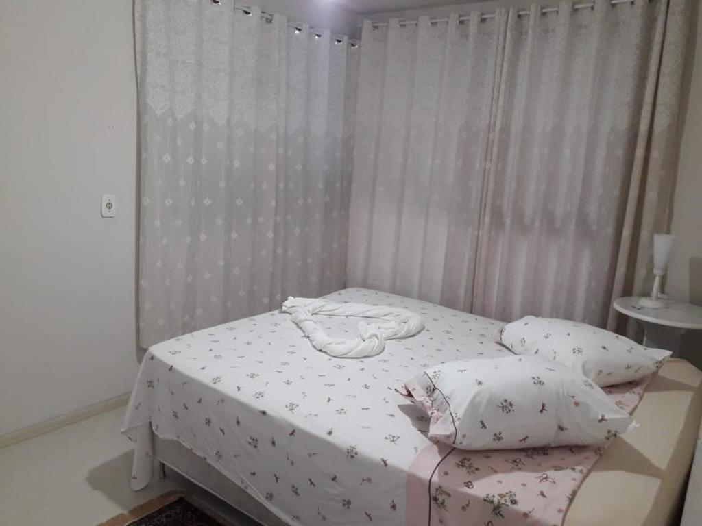 a bedroom with a bed with white sheets and pillows at Serra Gaúcha Uva e Vinho in Bento Gonçalves