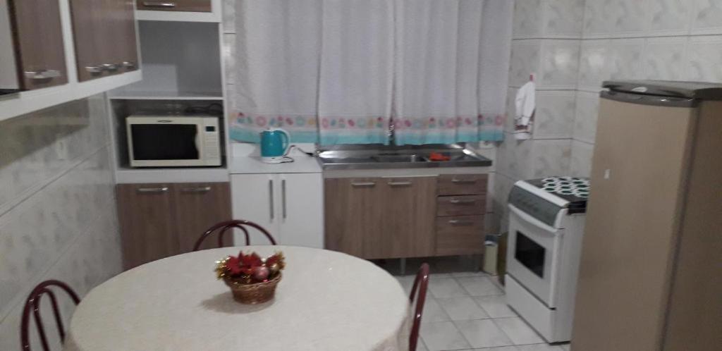 a small kitchen with a white table and a white refrigerator at Serra Gaúcha Uva e Vinho in Bento Gonçalves