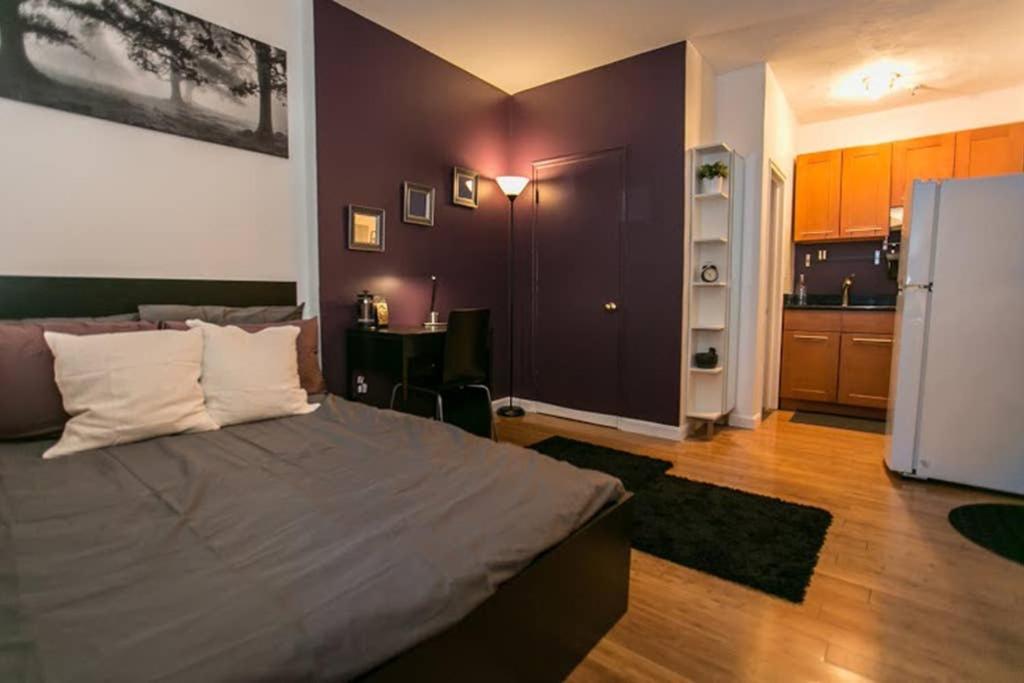 a bedroom with a large bed and a kitchen at Downtown Studio Apt, Near Tufts Med, BMC, MGH in Boston