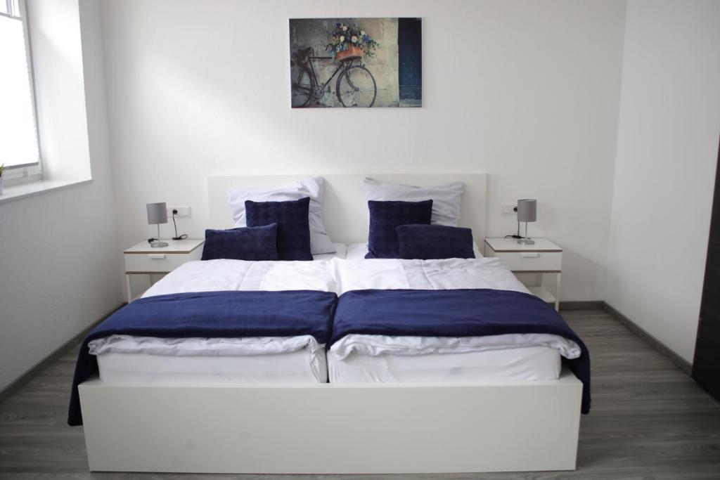 um quarto com uma grande cama branca com almofadas azuis em CityPension-Vreden em Vreden