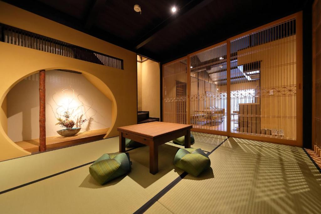 een kamer met een houten tafel en groene kussens bij Kyo no oozora SAIKA in Kyoto