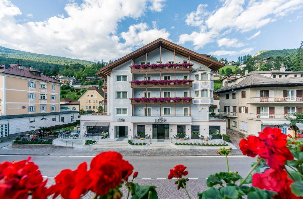 un gran edificio blanco con flores rojas delante en Hotel Genziana en Ortisei