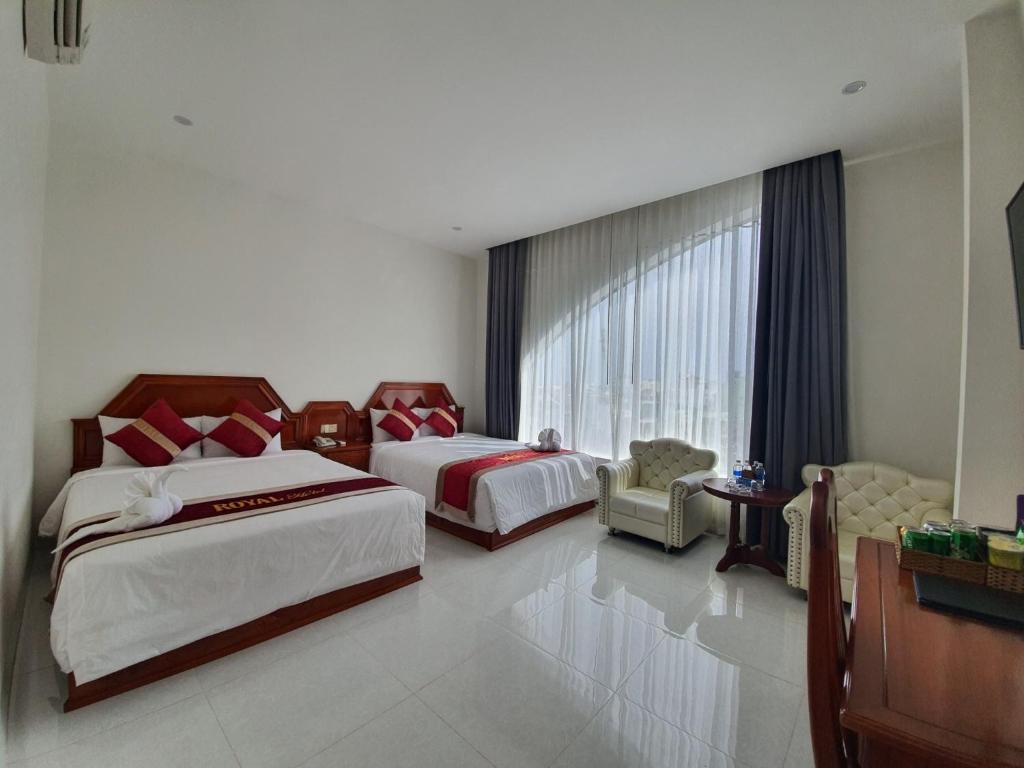Bạc LiêuにあるRoyal Hotelのベッド2台と窓が備わるホテルルームです。