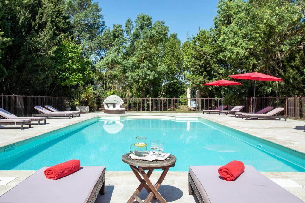 a swimming pool with chairs and a table next to it at Gîtes Domaine des Machottes in Grans
