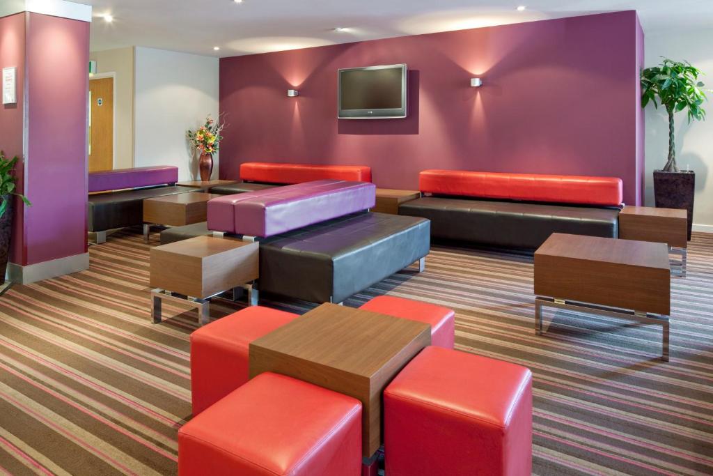 uma sala de espera com mobiliário colorido e uma televisão em Holiday Inn Express Poole, an IHG Hotel em Poole