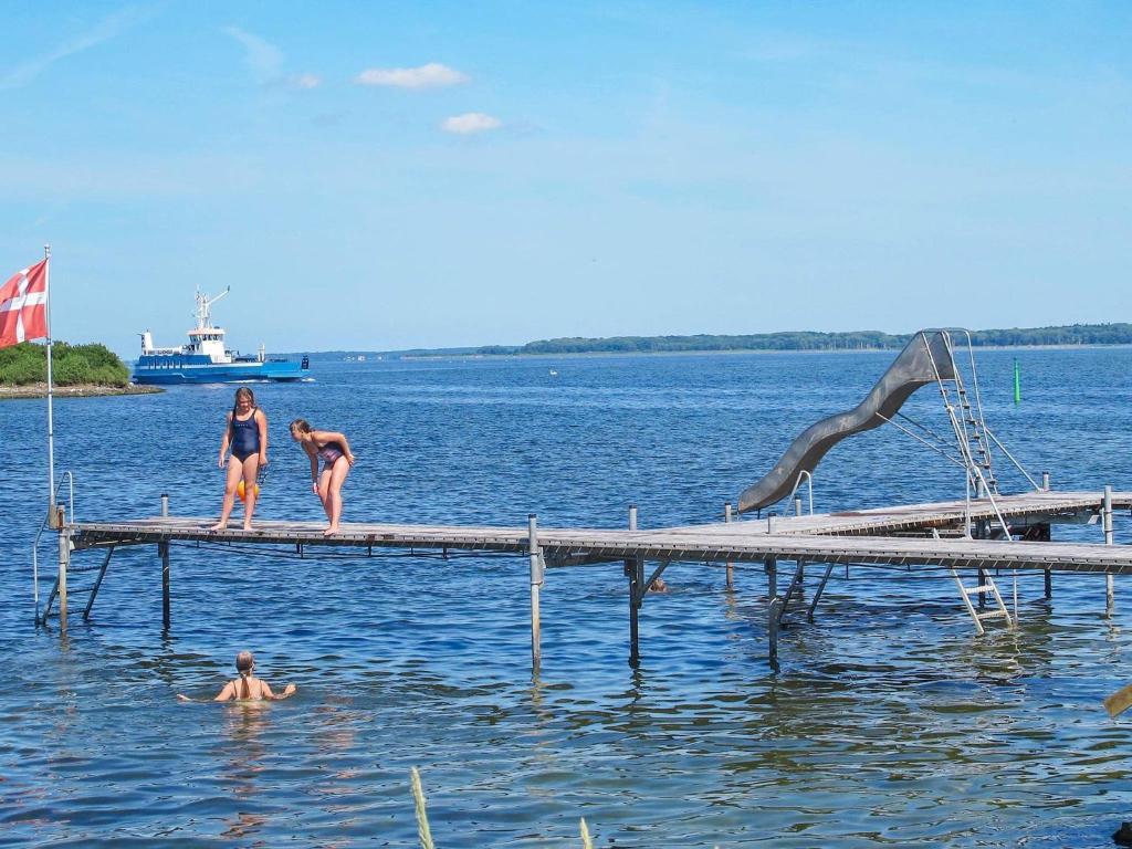 Tres mujeres están de pie en un muelle en el agua en 4 person holiday home in Bandholm, en Bandholm
