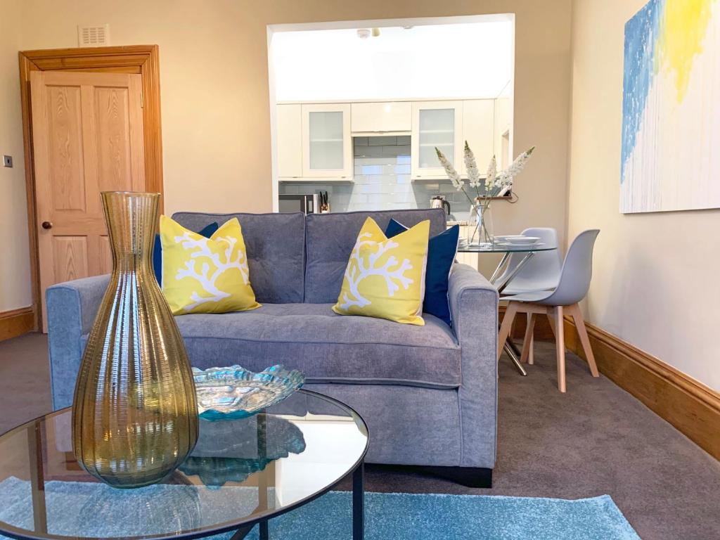 a living room with a blue couch and a glass table at Forest Park Apartment in Dundee