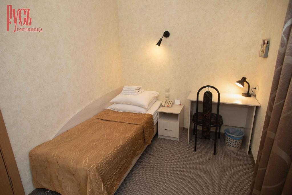 ein kleines Schlafzimmer mit einem Bett und einem Schreibtisch in der Unterkunft Гостиница Русь in Barnaul