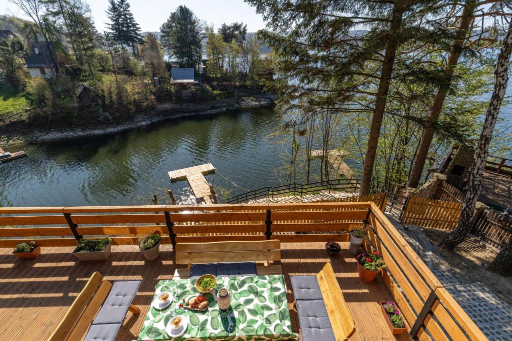 a table with a plate of food on a deck next to a river at Domek Rożnów in Rożnów