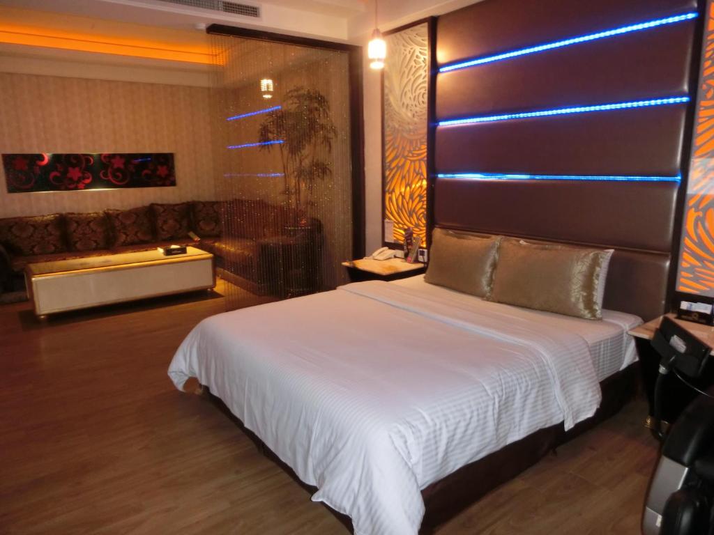 a bedroom with a large white bed and a couch at Blue Sky Motel in Guishan
