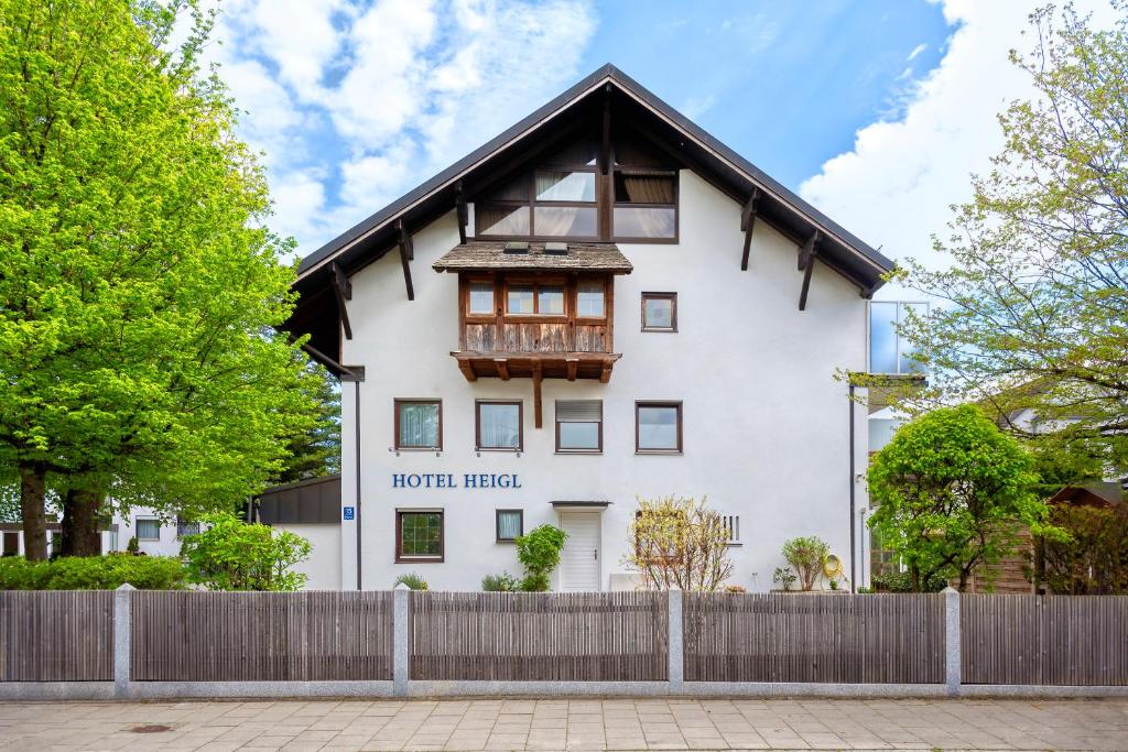 una casa blanca con una valla de madera delante de ella en Hotel Heigl, en Múnich