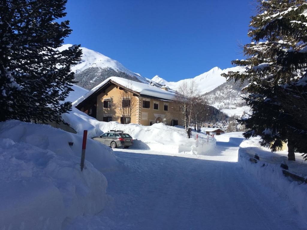 uma casa coberta de neve com um carro em frente em Chesa Viletta em La Punt-Chamues-ch