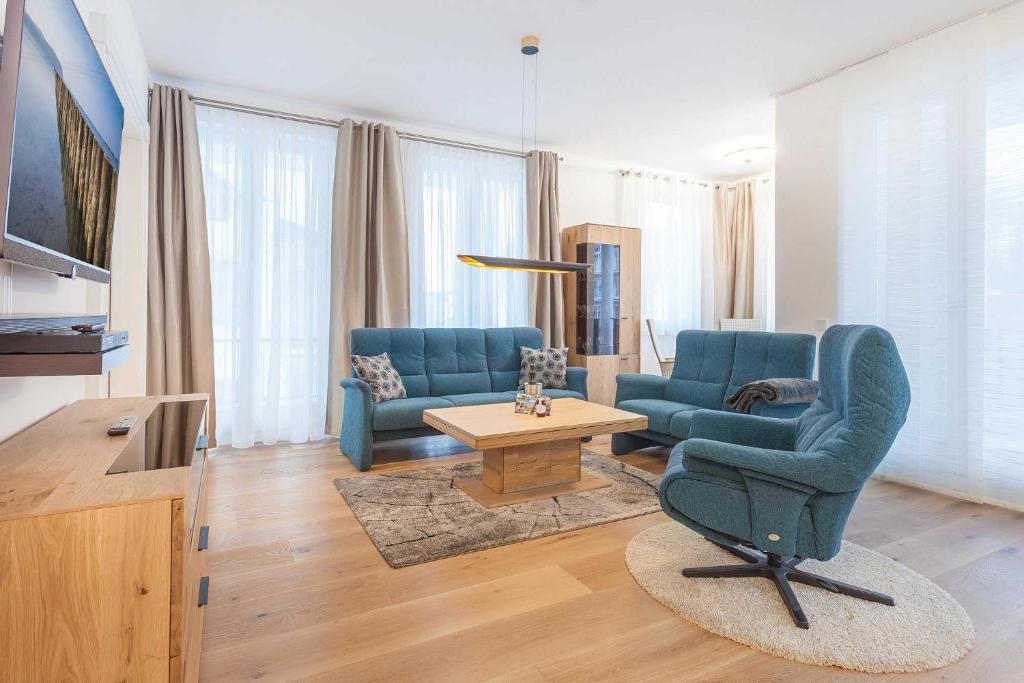a living room with two blue chairs and a table at FIRST Wellentraum in Ostseebad Sellin