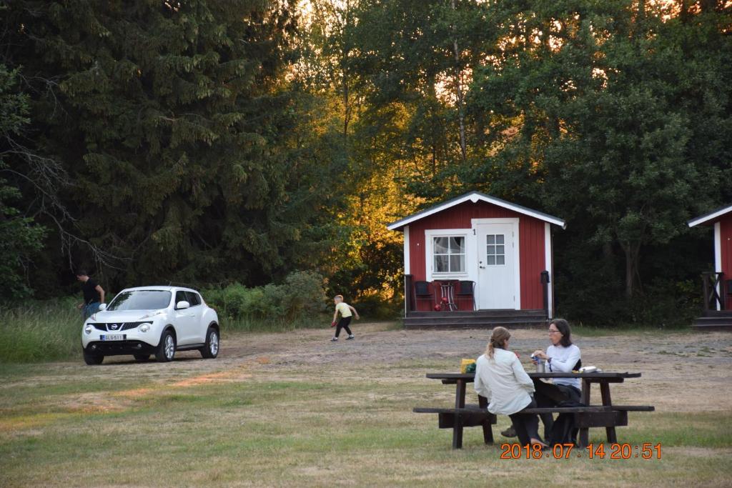 two women sitting at a picnic table in front of a car at Kapellskärs camping in Gräddö