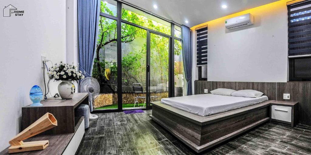 een slaapkamer met een bed en een groot raam bij F.Home Modern & Art 3BR Near My Khe Beach in Da Nang