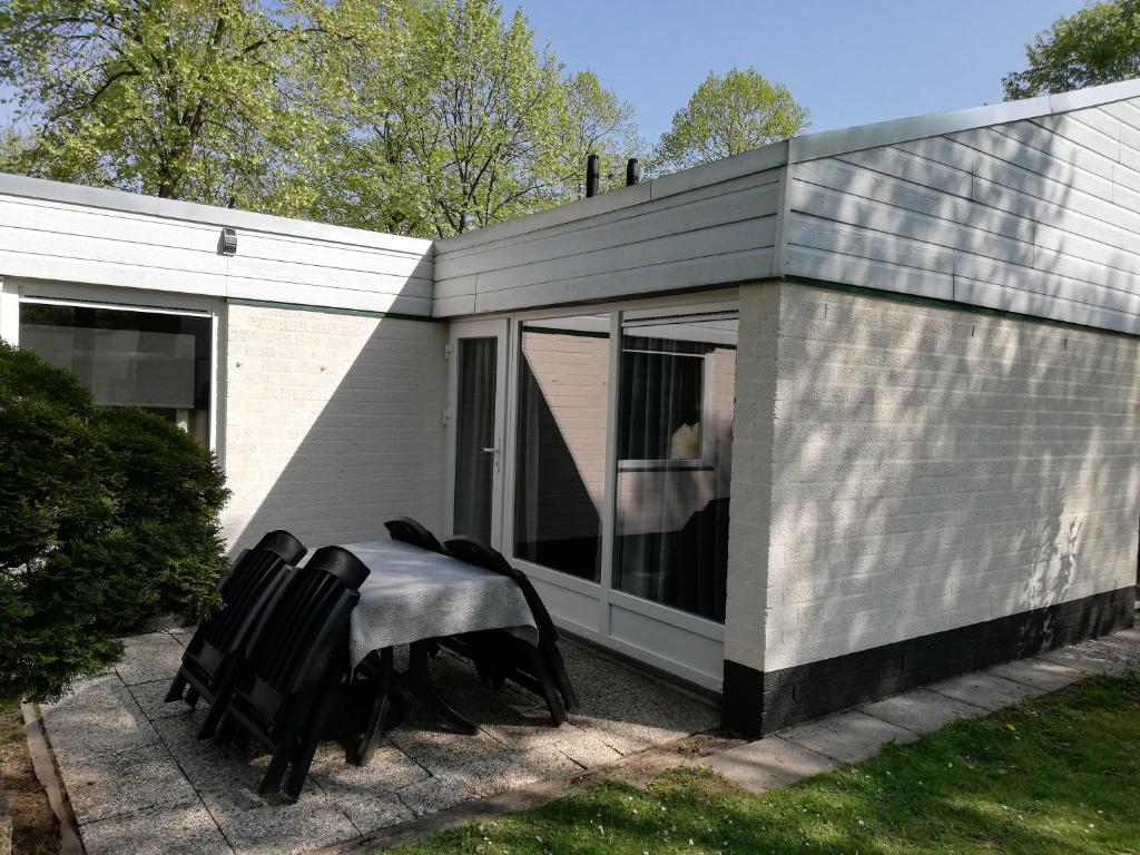 una pequeña casa con una mesa y sillas frente a ella en Rustige, gelijkvloerse vakantiewoning met 2 slaapkamers in Simpelveld, Zuid-Limburg, en Simpelveld