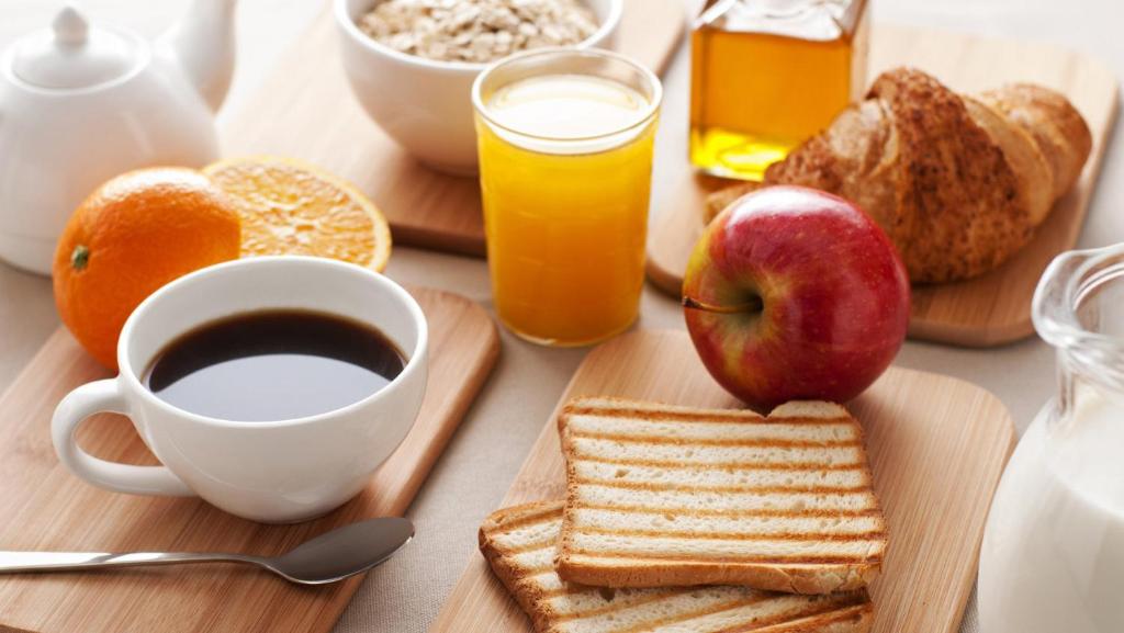 a table with breakfast foods and a cup of coffee at Hotel Reels - Residencial O TRINDADE in Águeda