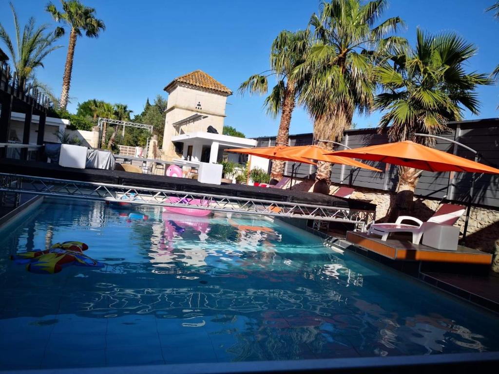 a swimming pool with chairs and umbrellas in a resort at Mas La Farelle Chambre d&#39;hote,Fitness &amp; Salle de jeux Gratuite &amp; SPA en supplément in Nîmes