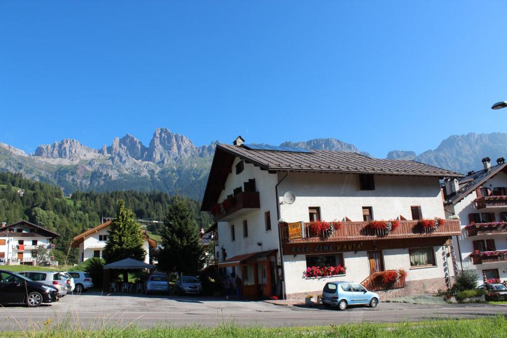 a building with cars parked in a parking lot with mountains at Hotel Cime d'Auta in Falcade