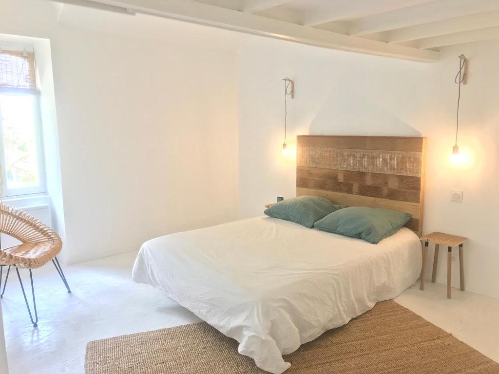 um quarto branco com uma cama e uma cadeira em La petite Noe em Vertou