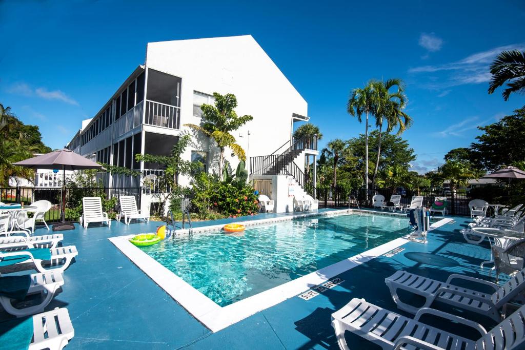 a swimming pool with chairs and a building at Marco Island Lakeside Inn in Marco Island