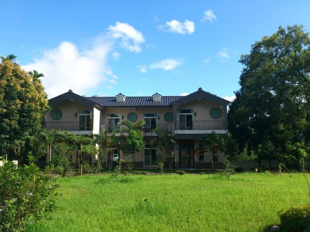 una casa con un campo verde delante de ella en Feng Lin Homestay, en Shuili