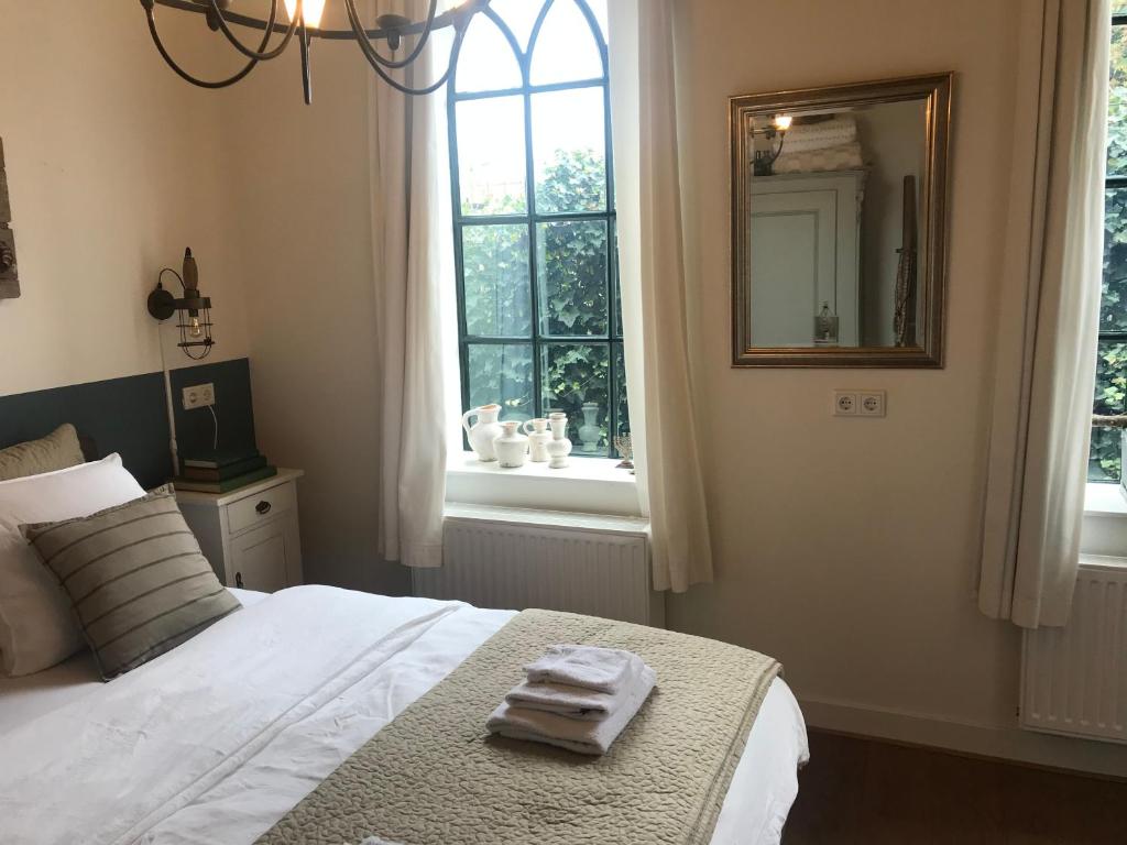 a bedroom with a bed with a mirror and a window at De vijgenhof in Appingedam