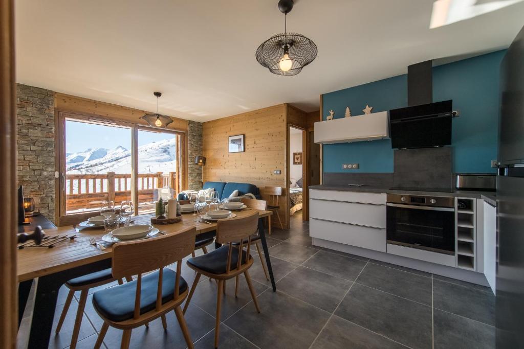 une cuisine et une salle à manger avec une table et des chaises dans l'établissement Appartement moderne et chaleureux sur les pistes, à La Toussuire