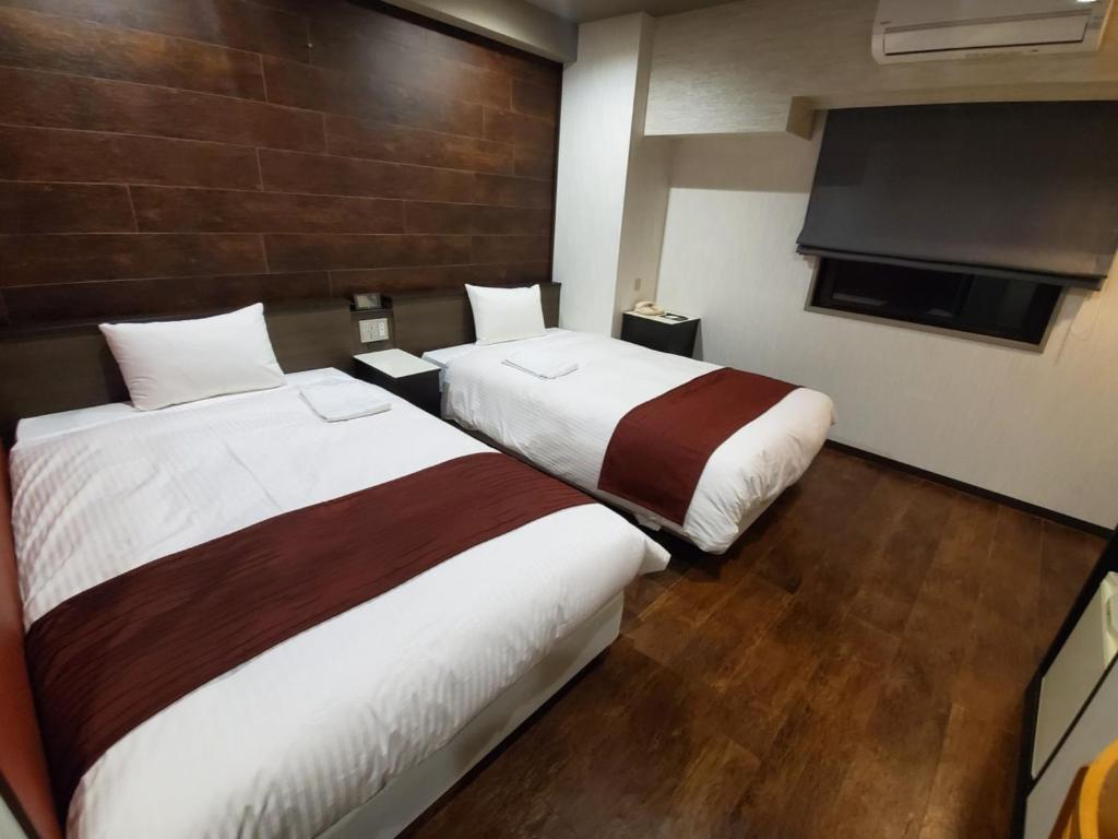 a hotel room with two beds and a flat screen tv at Hotel Ascent Hamamatsu / Vacation STAY 79775 in Hamamatsu