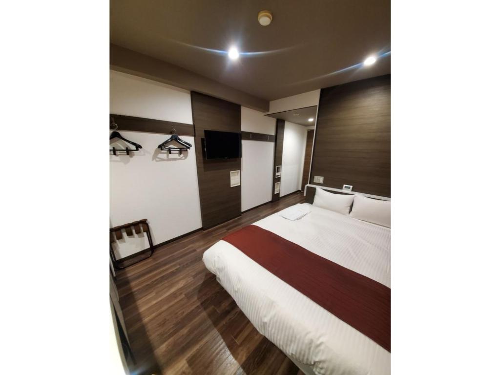 ein Hotelzimmer mit einem Bett und einem TV in der Unterkunft Hotel Ascent Hamamatsu / Vacation STAY 79771 in Hamamatsu