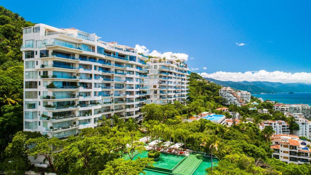 a large building on a hill next to a body of water at AVALON - 1002 Amapas Bay Bliss with Private Pool in Puerto Vallarta