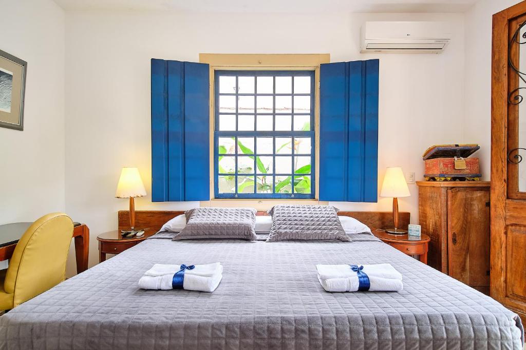 a bedroom with a large bed with towels on it at Pousada Pontal Gardens in Paraty