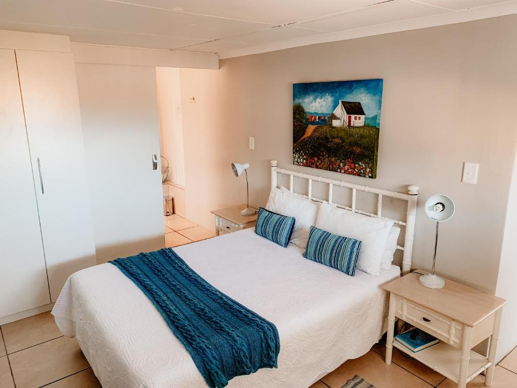 a bedroom with a white bed and a painting on the wall at Sunbird View in Langebaan