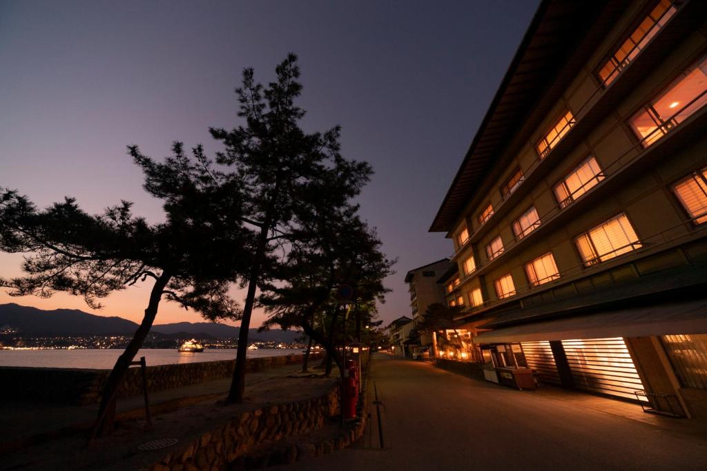 a building with a tree in front of the water at Hotel Miya Rikyu in Miyajima