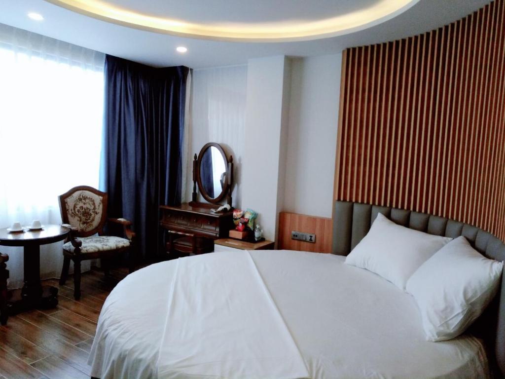 una camera con letto bianco e specchio di ABAY Hotel a Nha Trang