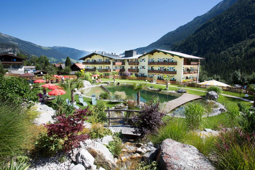 a resort in the mountains with a pond and a bridge at Nationalparkhotel Klockerhaus in Krimml