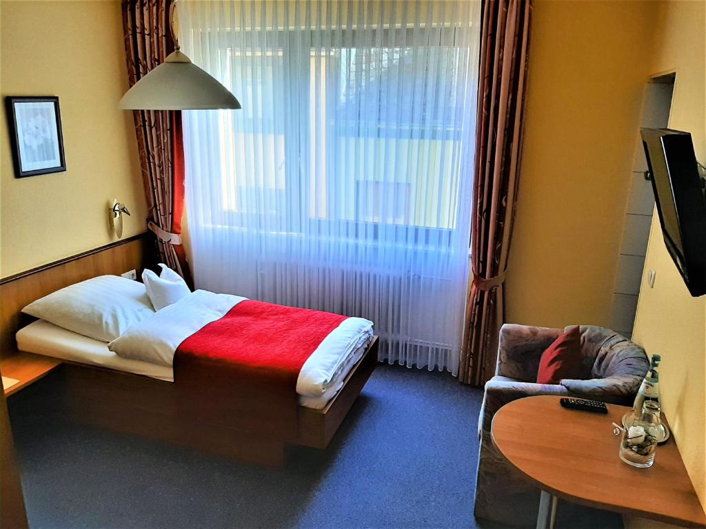 ein Schlafzimmer mit einem Bett, einem Stuhl und einem Fenster in der Unterkunft Weinhotel Hubertus Garni in Klotten