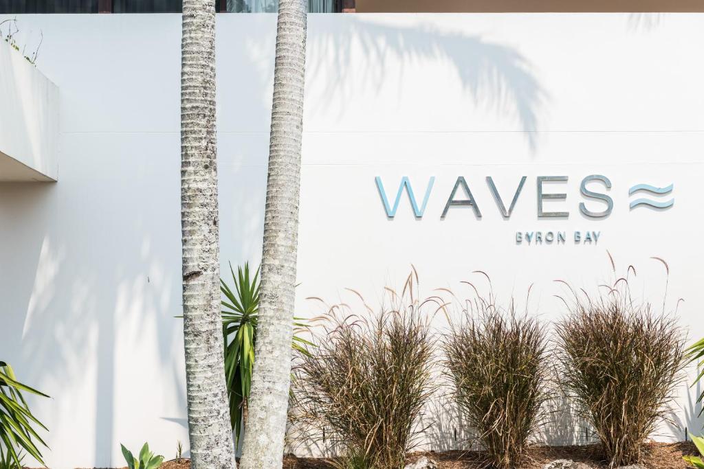 a sign for the wessex sharayanayan bay in front of palm trees at Waves Byron Bay in Byron Bay