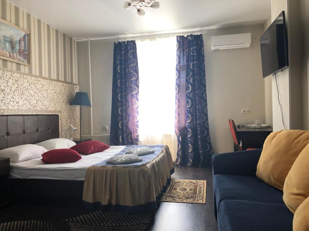モスクワにあるKONCERT.RU™ HOTELのベッドルーム1室(ベッド1台、ソファ、窓付)