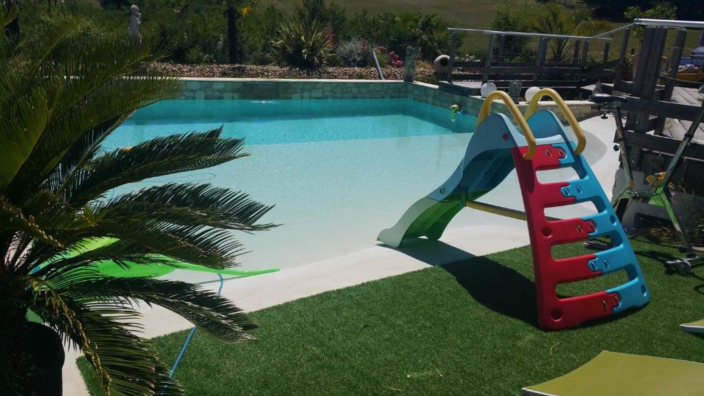 a slide in the grass next to a swimming pool at B&B chez EVA en Périgord in Le Buisson de Cadouin