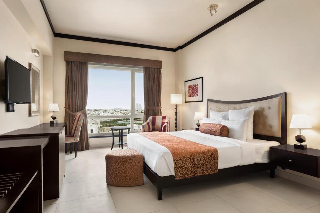 カラチにあるRamada by Wyndham Karachi Creekのベッドと大きな窓が備わるホテルルームです。