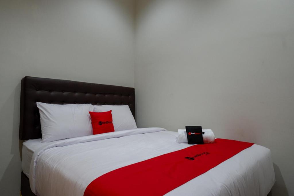 a bed with red pillows and a red blanket on it at RedDoorz Syariah near Alun Alun Kebumen in Kebumen