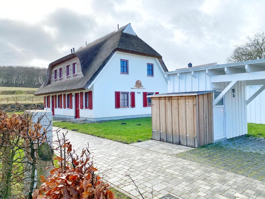 une maison blanche avec un toit noir et des portes rouges dans l'établissement Doppelhaushälfte Freyh 1 am Golfplatz, à Ranzow